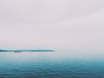 Minimalist seascape with distant boat on calm blue water