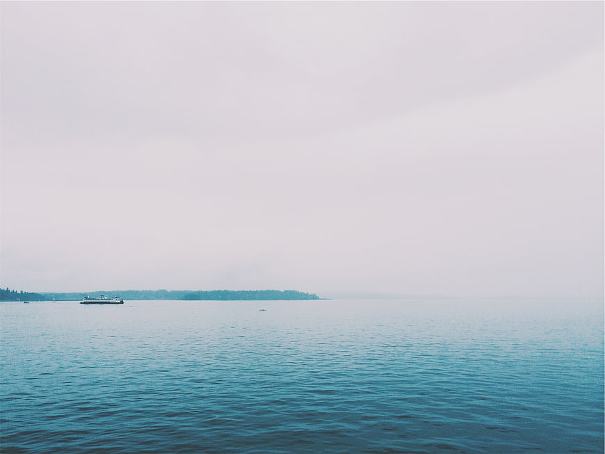 Minimalist seascape with distant boat on calm blue water