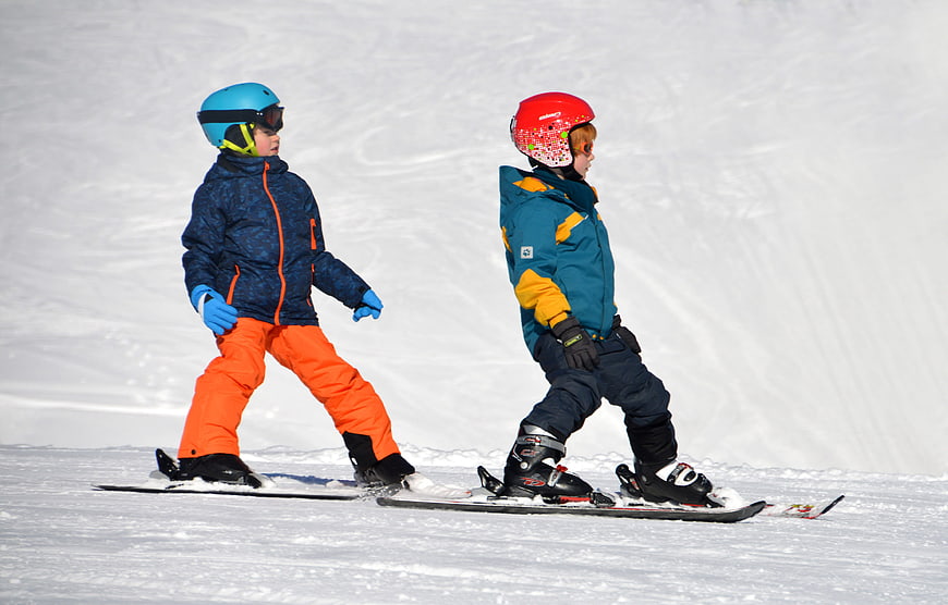 Two young children skiing on a snowy slope