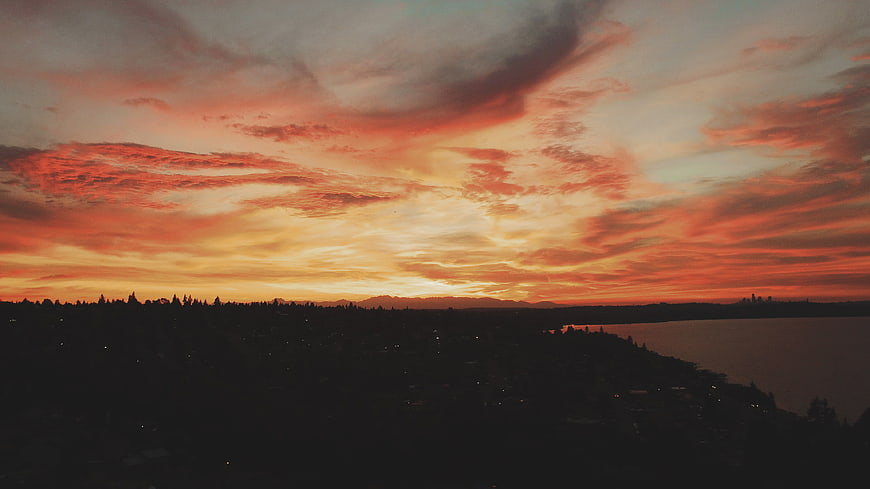 Dramatic Sunset Sky Over Silhouetted City and Water