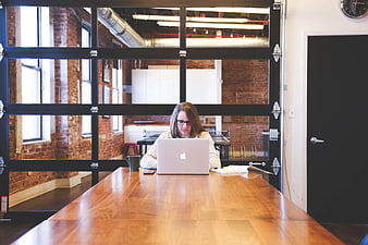 Woman working on laptop in modern office with brick walls