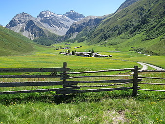 Scenic Alpine Valley with Wooden Fence and Mountain Village
