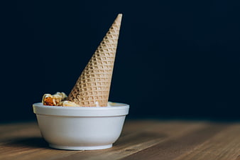 Ice cream cone in white bowl on wooden table