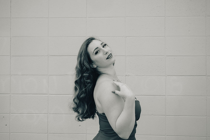 Monochrome Portrait of Woman in Black Dress Against Brick Wall