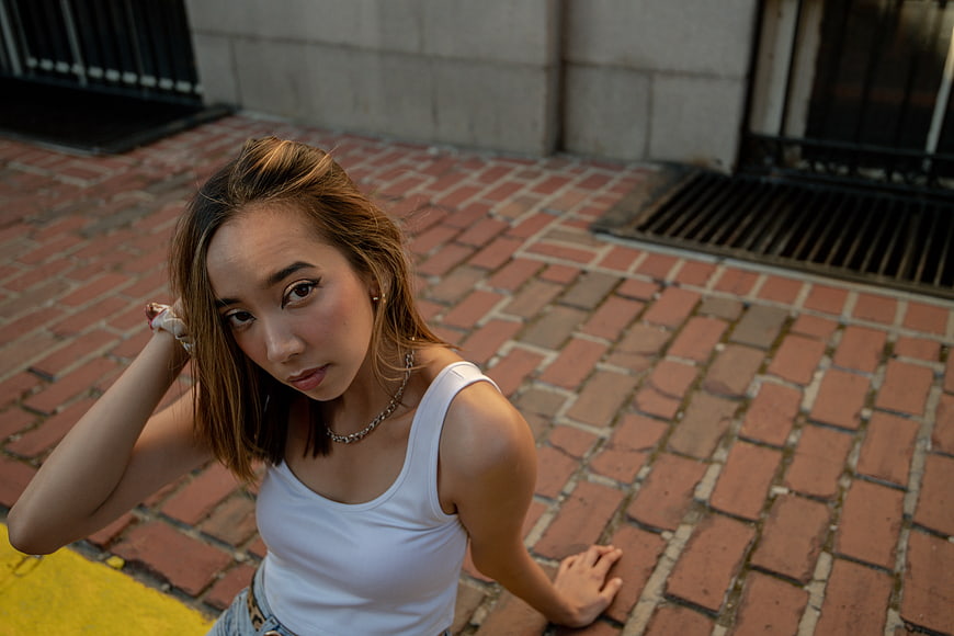 High angle portrait of young woman sitting on brick pavement