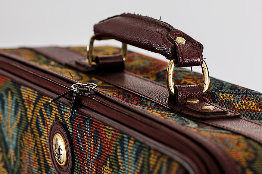 Close-up of vintage patterned suitcase with leather handle