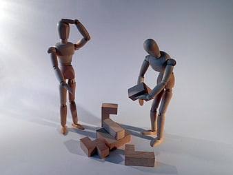 Wooden mannequins solving puzzle with blocks