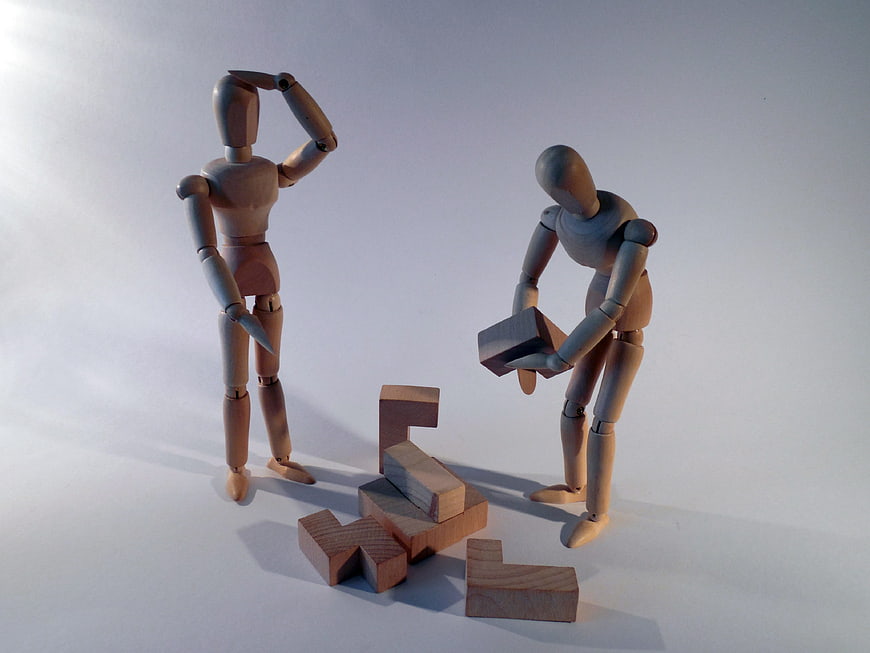 Wooden mannequins solving puzzle with blocks