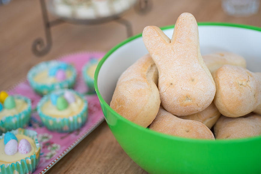 Easter bunny bread rolls in green bowl with cupcakes