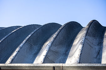 Close-up of curved corrugated metal roof against blue sky