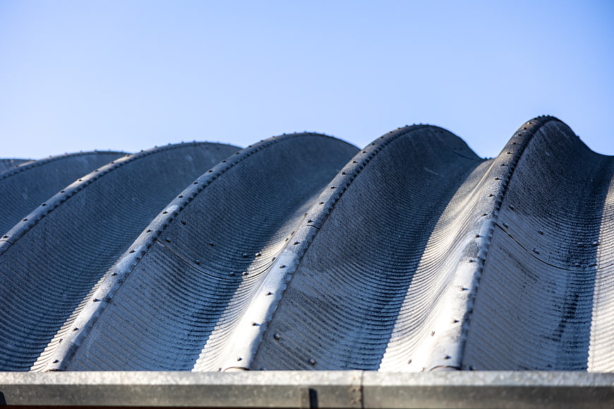 Close-up of curved corrugated metal roof against blue sky