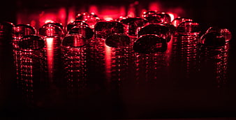 Red glass beads on reflective surface with dramatic lighting