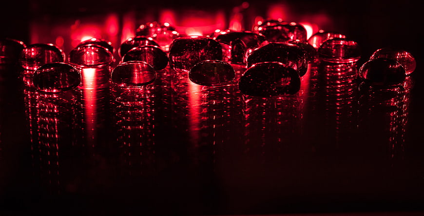 Red glass beads on reflective surface with dramatic lighting