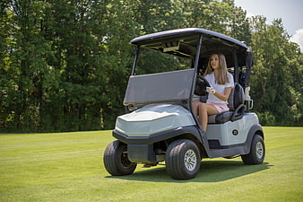 Woman driving a golf cart on a sunny green course