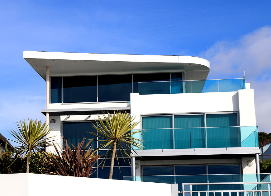 Modern white house with blue glass windows and palm trees