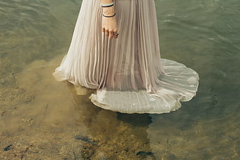 Woman in beige dress standing in shallow water