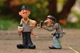 Humorous ceramic figurines of a journalist and photographer in an outdoor setting
