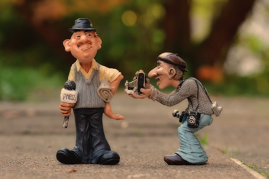 Humorous ceramic figurines of a journalist and photographer in an outdoor setting