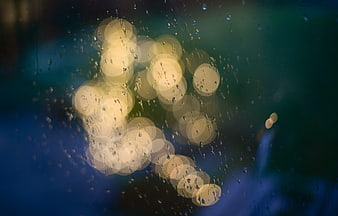 Raindrops on glass with blurred city lights bokeh background