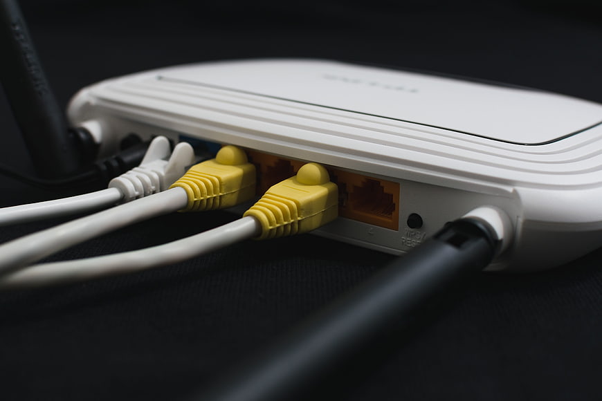 Close-up of white Wi-Fi router with yellow ethernet cables