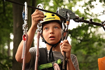 Young Boy Ziplining in Forest with Safety Helmet