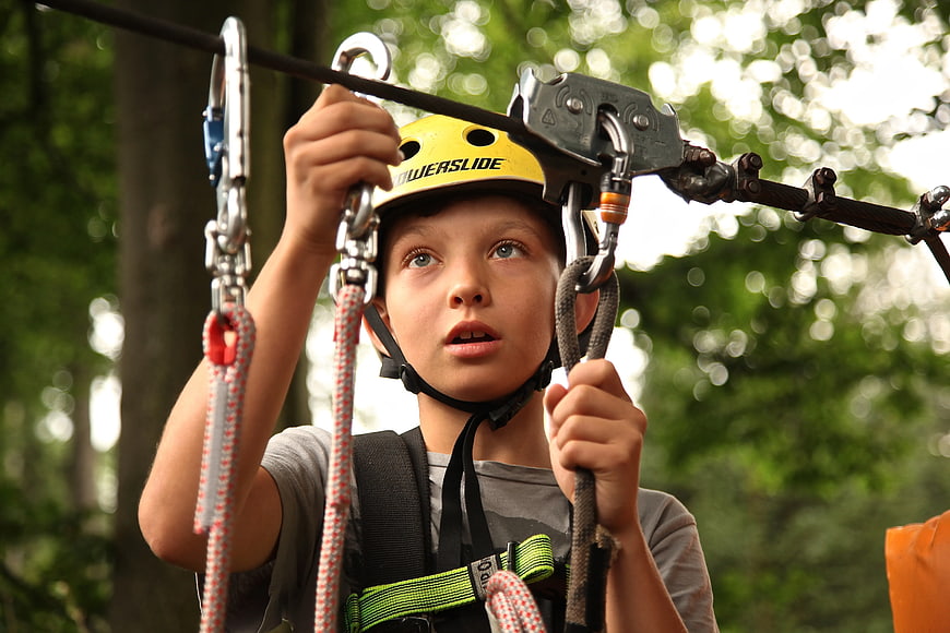 Young Boy Ziplining in Forest with Safety Helmet