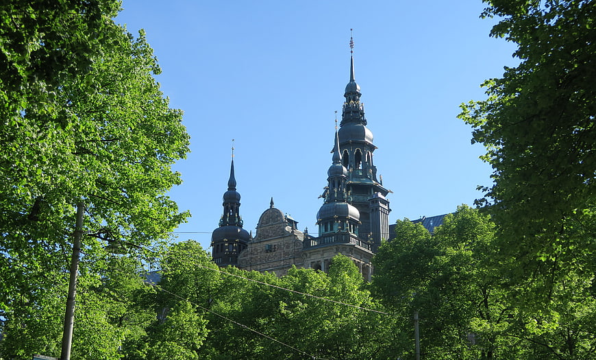 Baroque church spires framed by green trees against blue sky