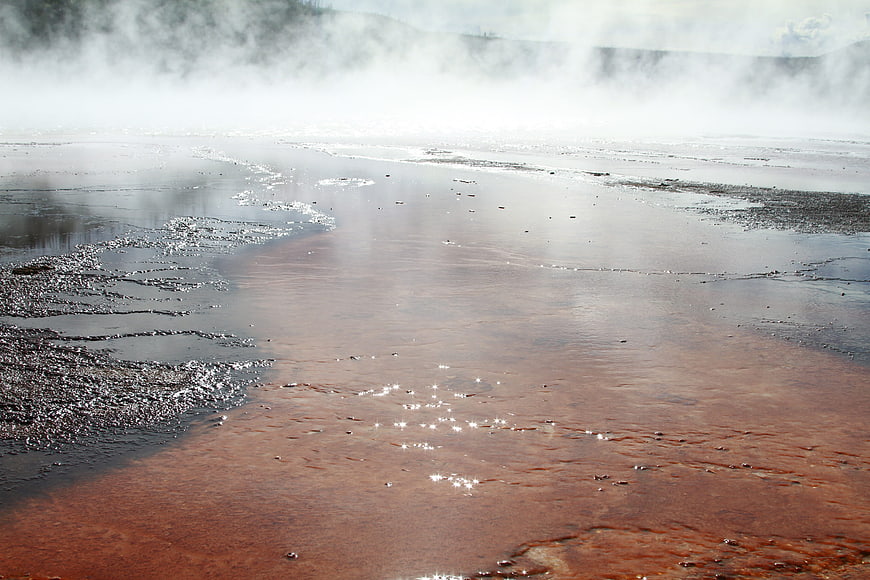 Steaming Hot Spring with Rust-Colored Water and Mineral Deposits