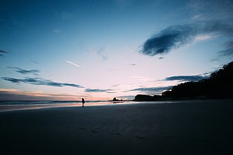 Silhouette of Surfer Walking on Beach at Sunset