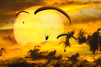 Paragliders Silhouetted Against Dramatic Golden Sunset Sky