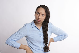 Frustrated young woman with hands on hips in blue shirt