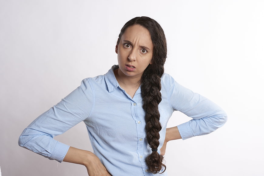 Frustrated young woman with hands on hips in blue shirt