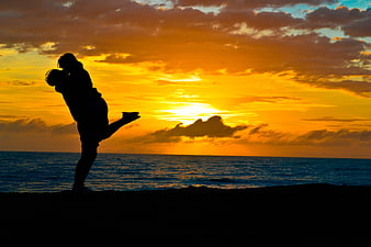 Silhouette of Couple Kissing on Beach at Sunset