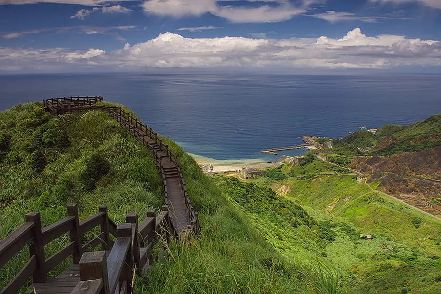 Wooden boardwalk path on green hill overlooking ocean