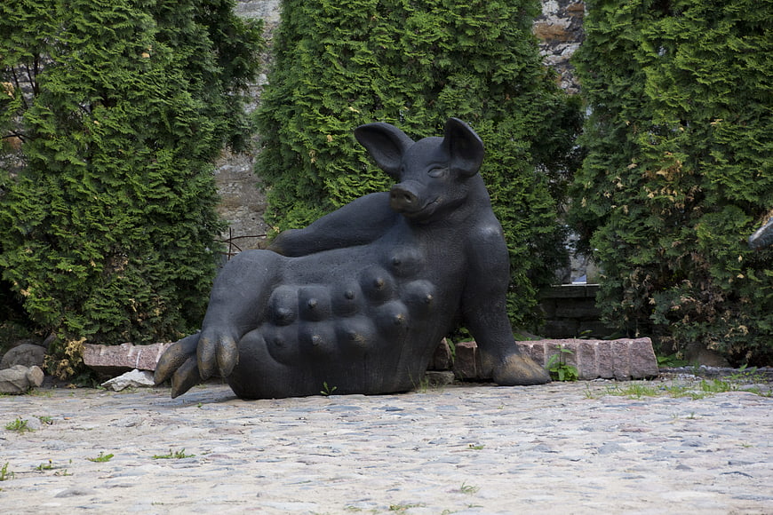 Bronze Statue of a Relaxed Pig in a Garden