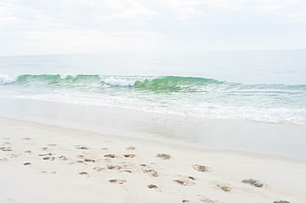 Serene Beach Scene with Footprints in Sand and Gentle Waves