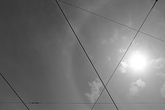 Black and white sky with power lines and sun