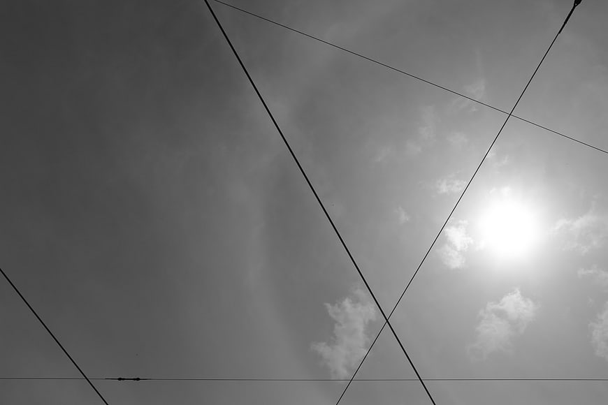 Black and white sky with power lines and sun