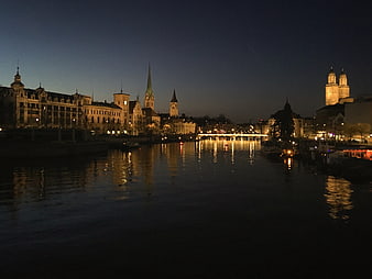 Night cityscape of Regensburg skyline with illuminated church spires and river reflections