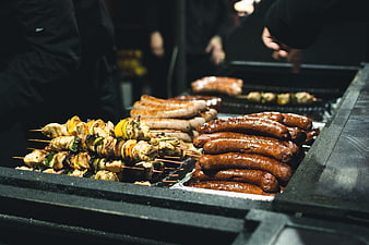Grilled sausages and chicken skewers on a street food grill