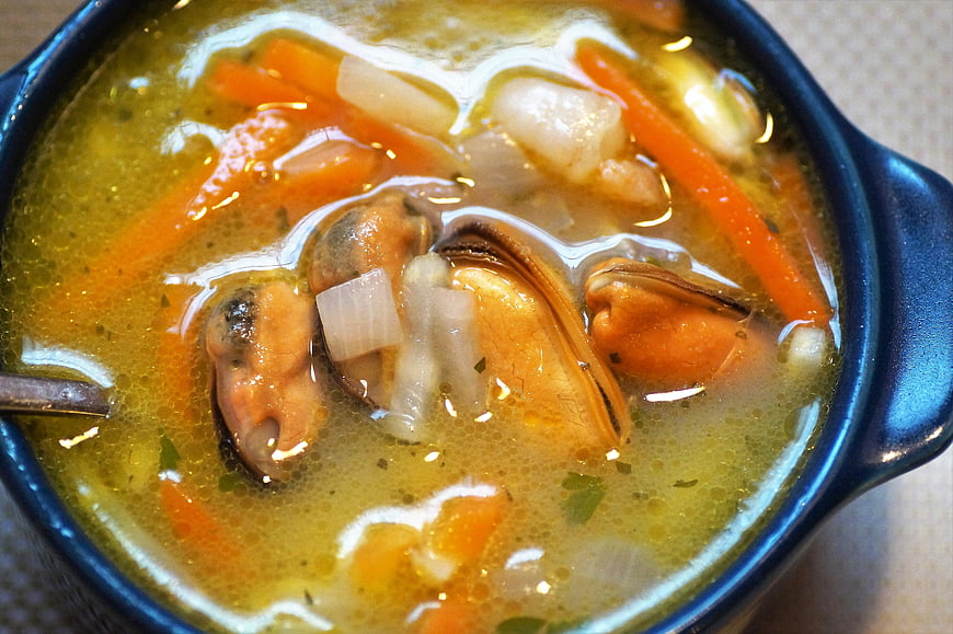 Close-up of steaming seafood soup with mussels and carrots