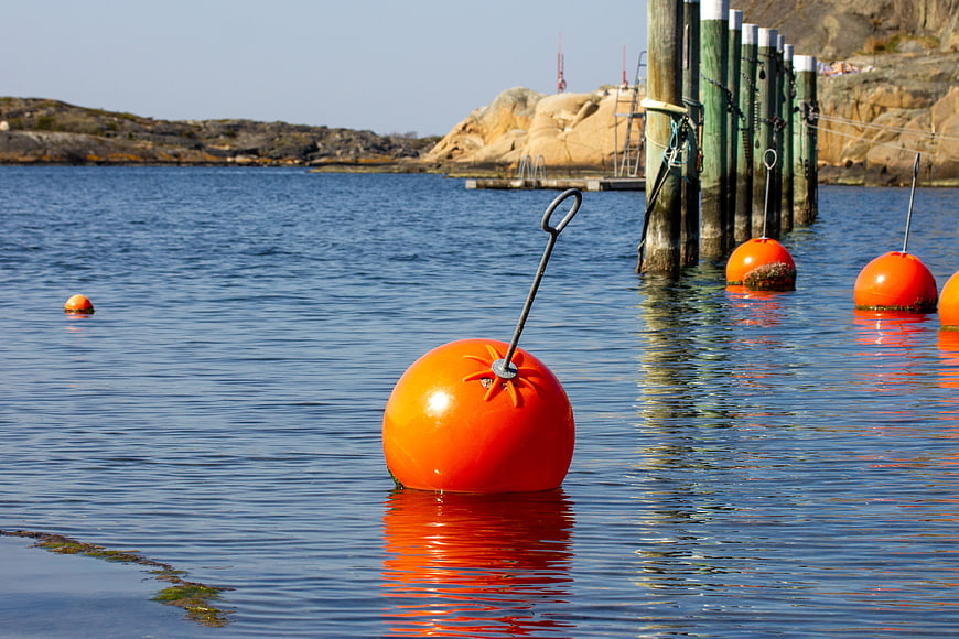 Bright orange buoy floating in calm blue harbor water