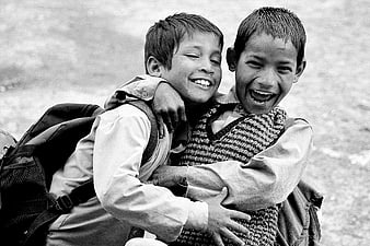 Two happy schoolboys hugging and laughing outdoors