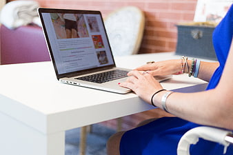 Woman Typing on Laptop at White Desk