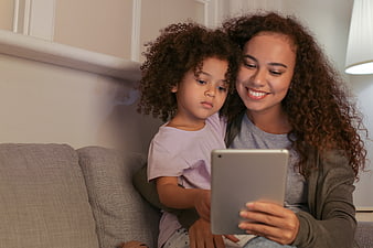 Mother and daughter using tablet together on couch