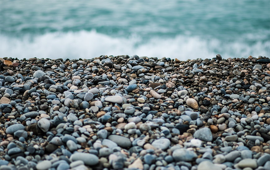 Close-up of smooth pebbles on a rocky beach with blurred ocean waves