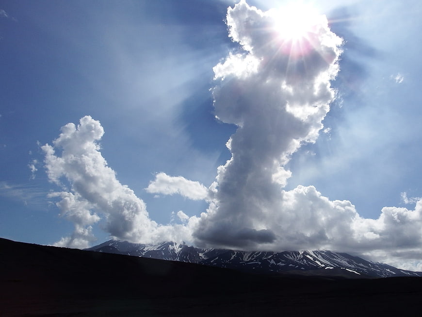 Dramatic Sun Rays Through Clouds Over Snowy Mountains