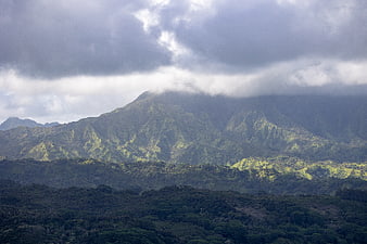 Dramatic lush green mountain range under cloudy sky