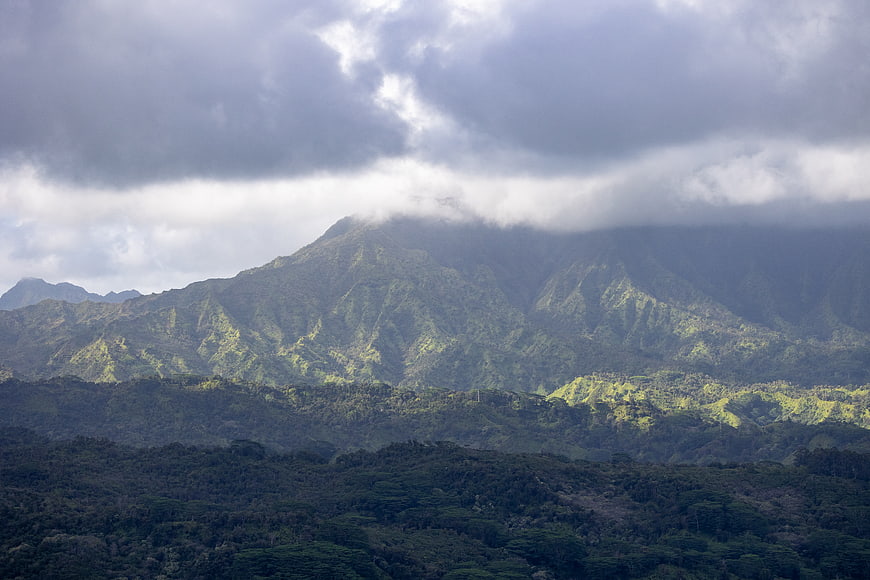 Dramatic lush green mountain range under cloudy sky