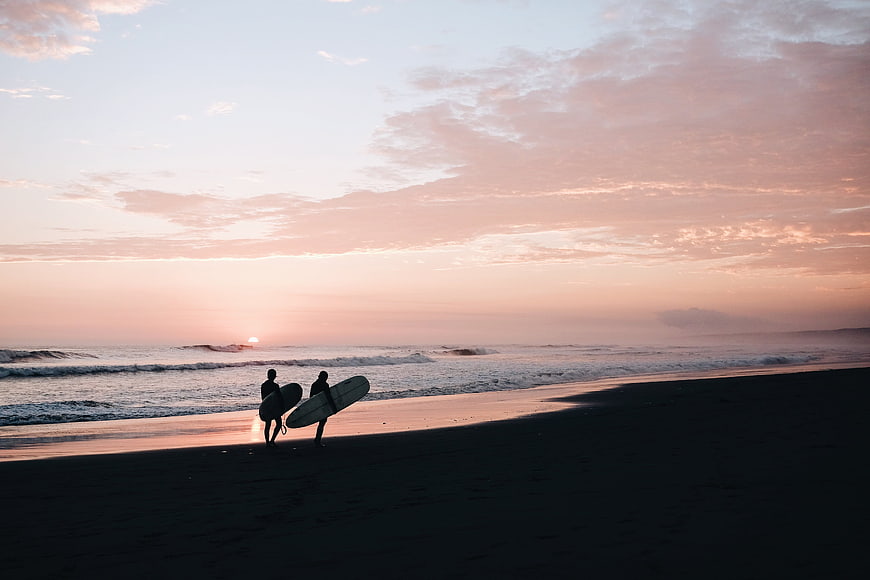 Silhouetted Surfers Walking on Beach at Sunset